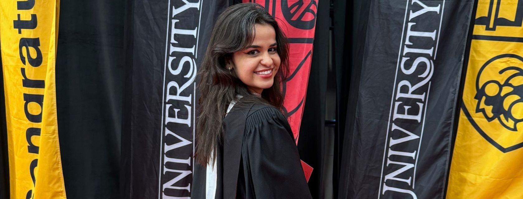 Julia Moraes standing in front of U of G banners at her grad.