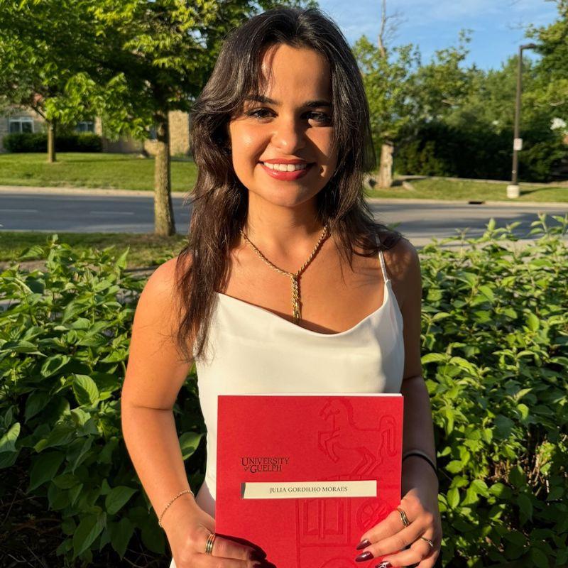 Grad with their degree standing outside.