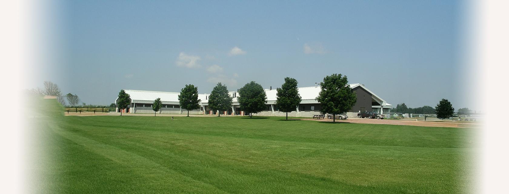 Exterior landscape view of the Ponsonby General Animal Facility, a large, modern, L-shaped barn