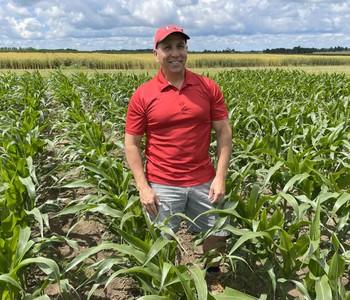 Dr. Lauzon standing in a corn field with a blue sky.