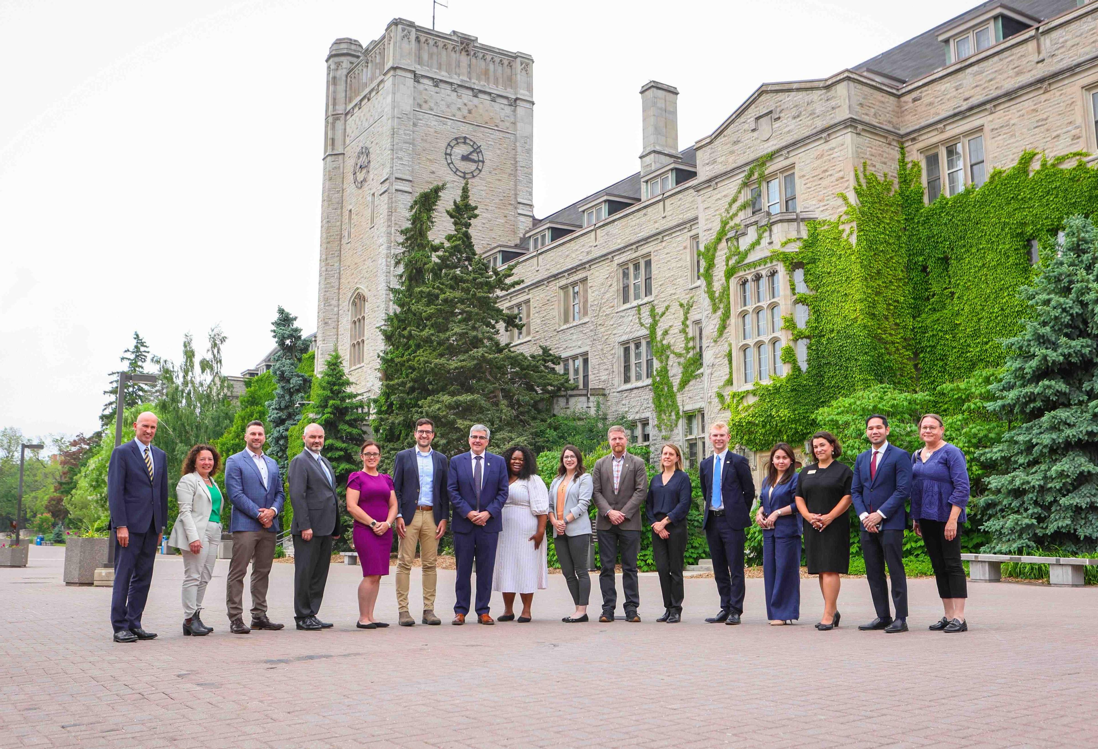 Attaches and U of G senior leaders stand in a row in front of Johnston Hall