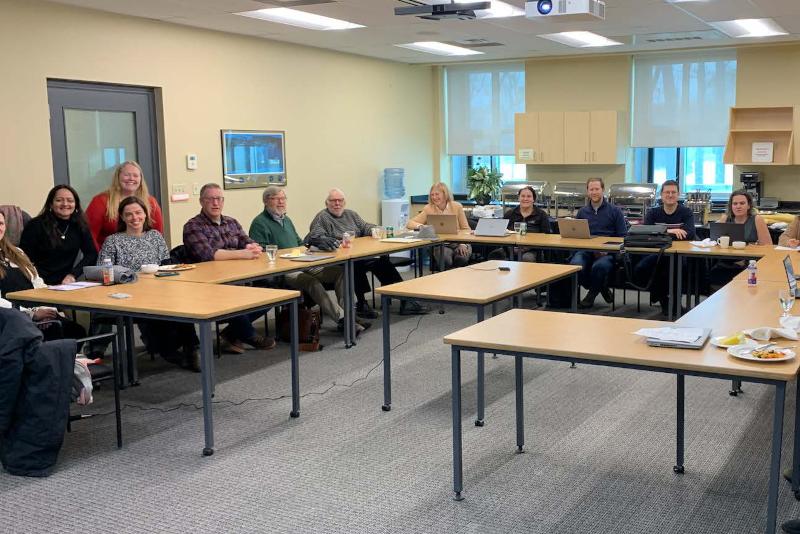 A meeting with many people sitting around a room