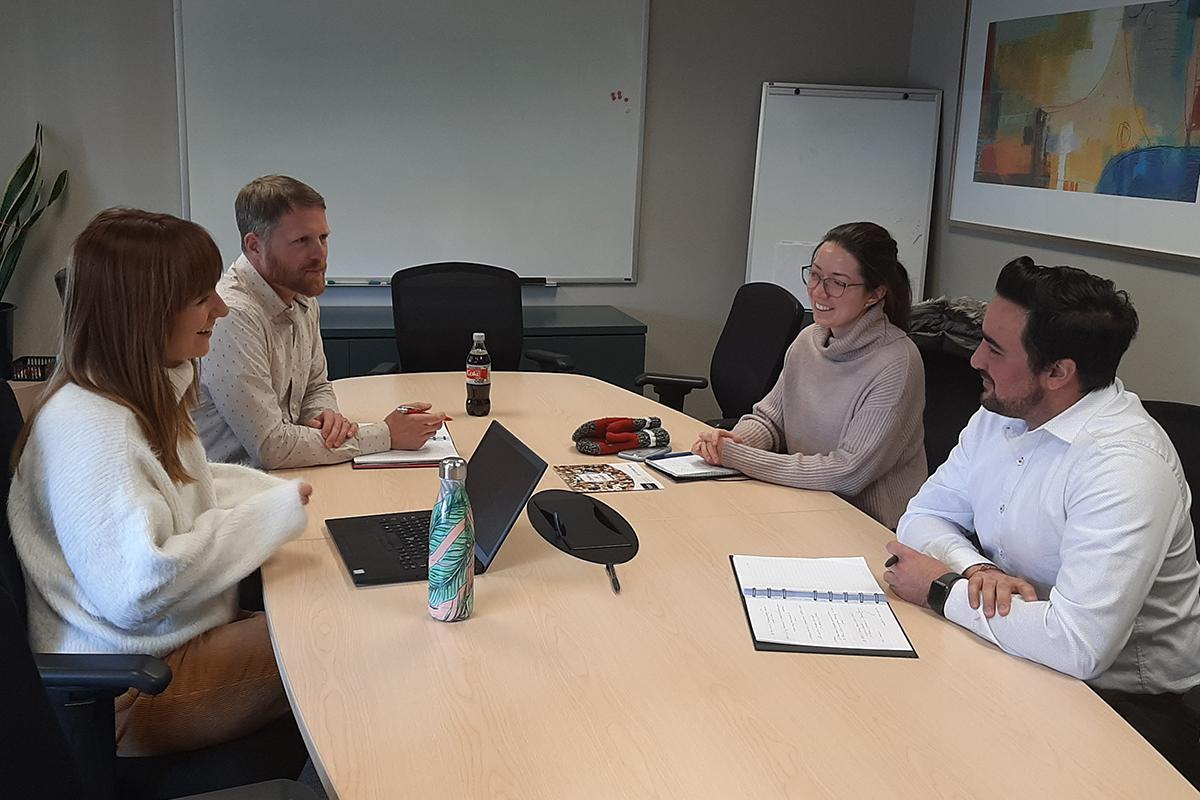 Four people sitting at a conference table talking