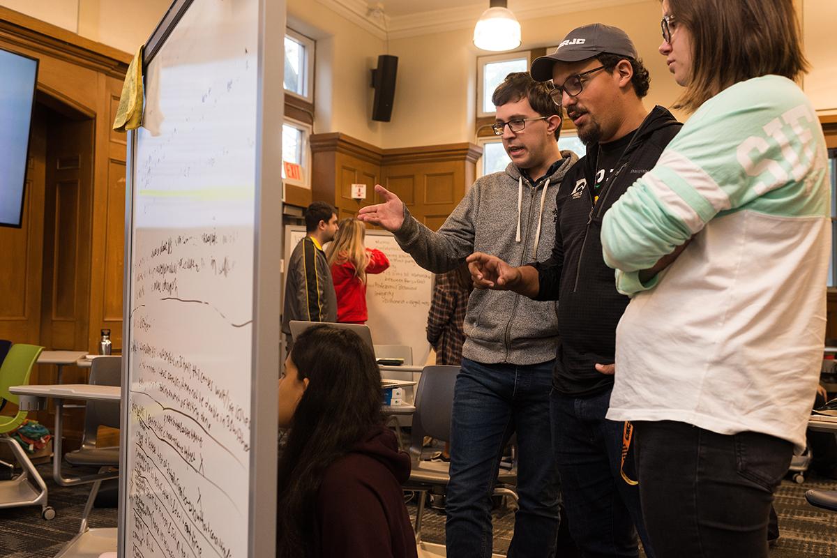 Three students looking at a whiteboard