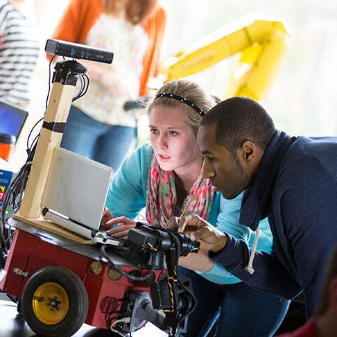 A man and a woman programming a robot