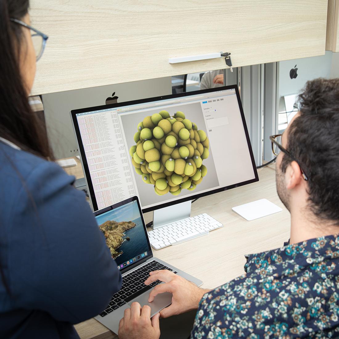 A man and a woman looking at a screen of a bacteria