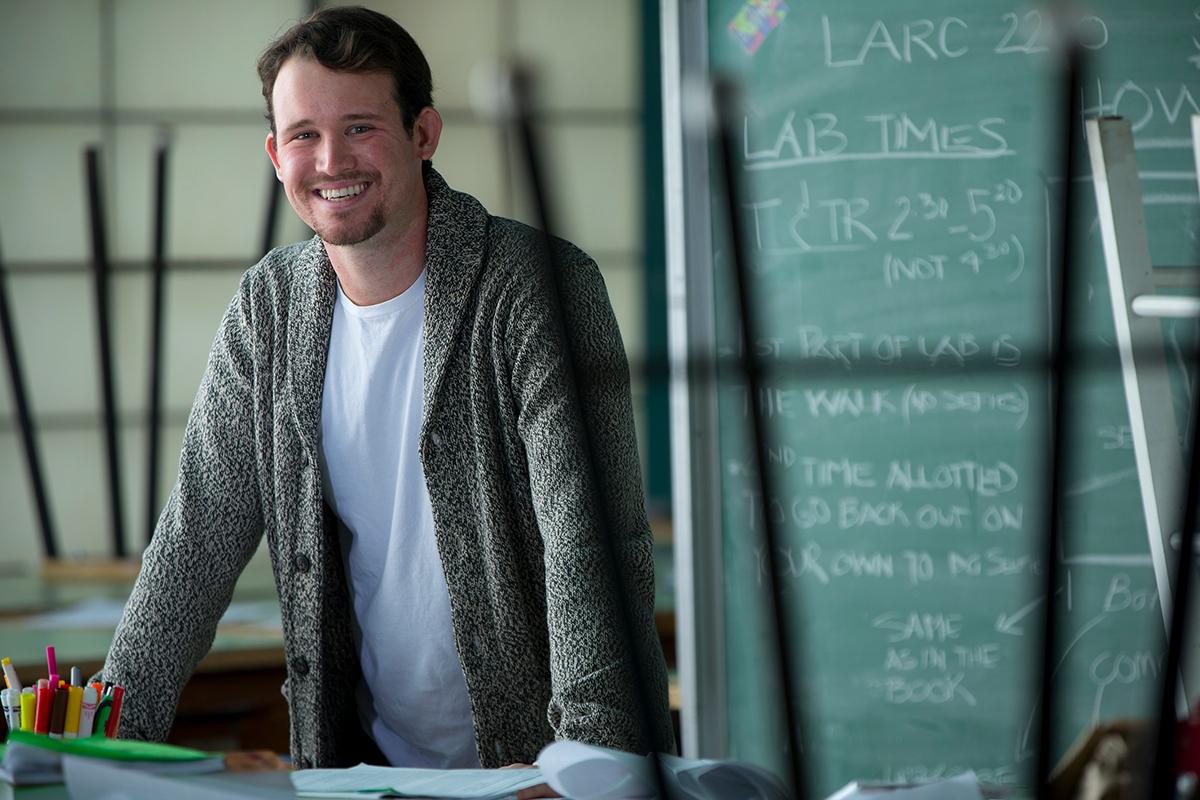A man smiling by a chalkboard