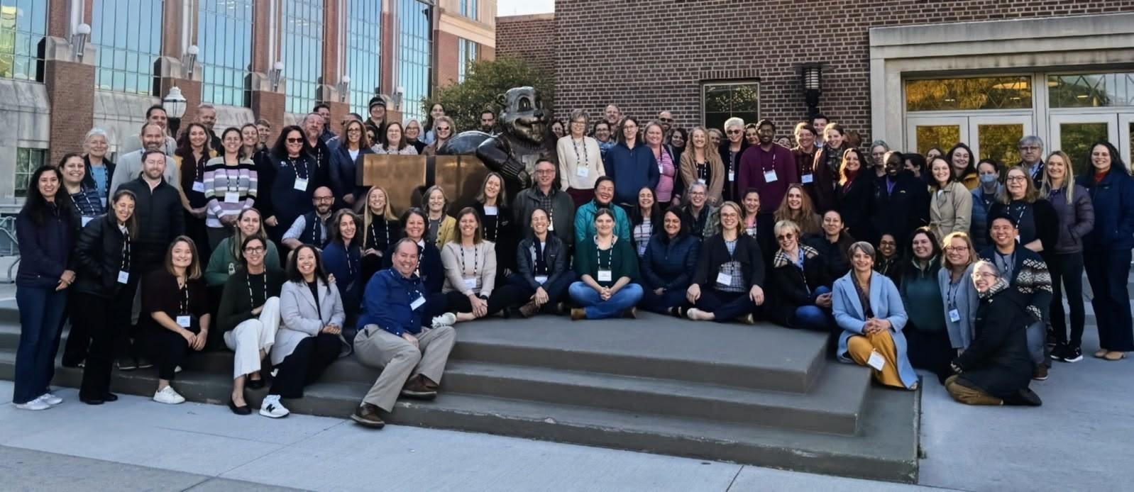 A large group of people outside in front of a red brick building.