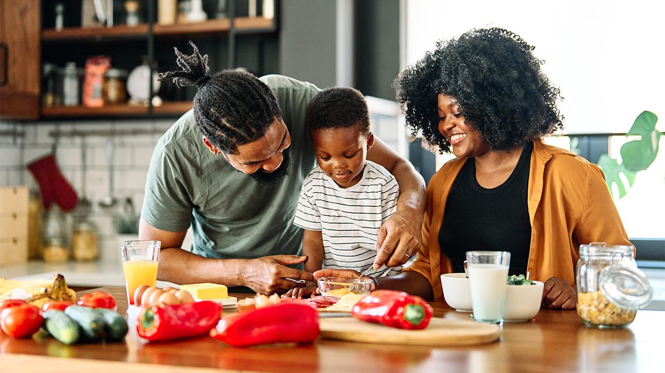 Parents teach their young child cooking skills