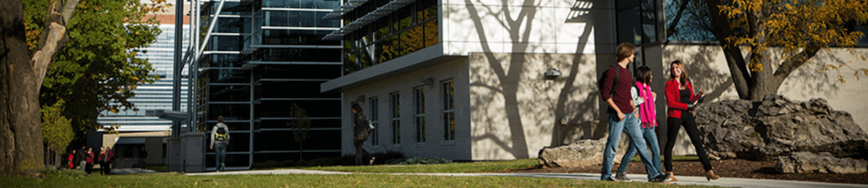 Three people walking together outside of Alexander Hall