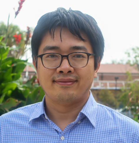Dr James Ji in a garden wearing a blue button down shirt