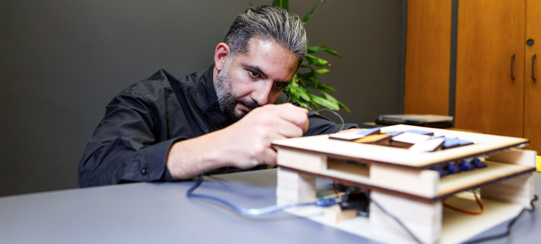 Professor Afshin Ashari adjusting something on a model with a focused look on his face