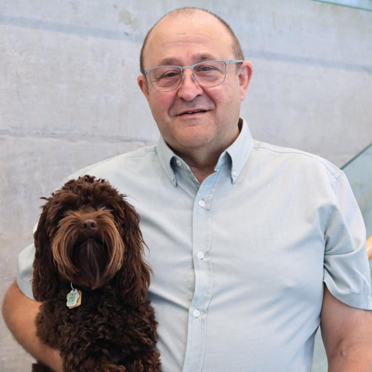 caucasian man with glasses, holding a small brown poodle