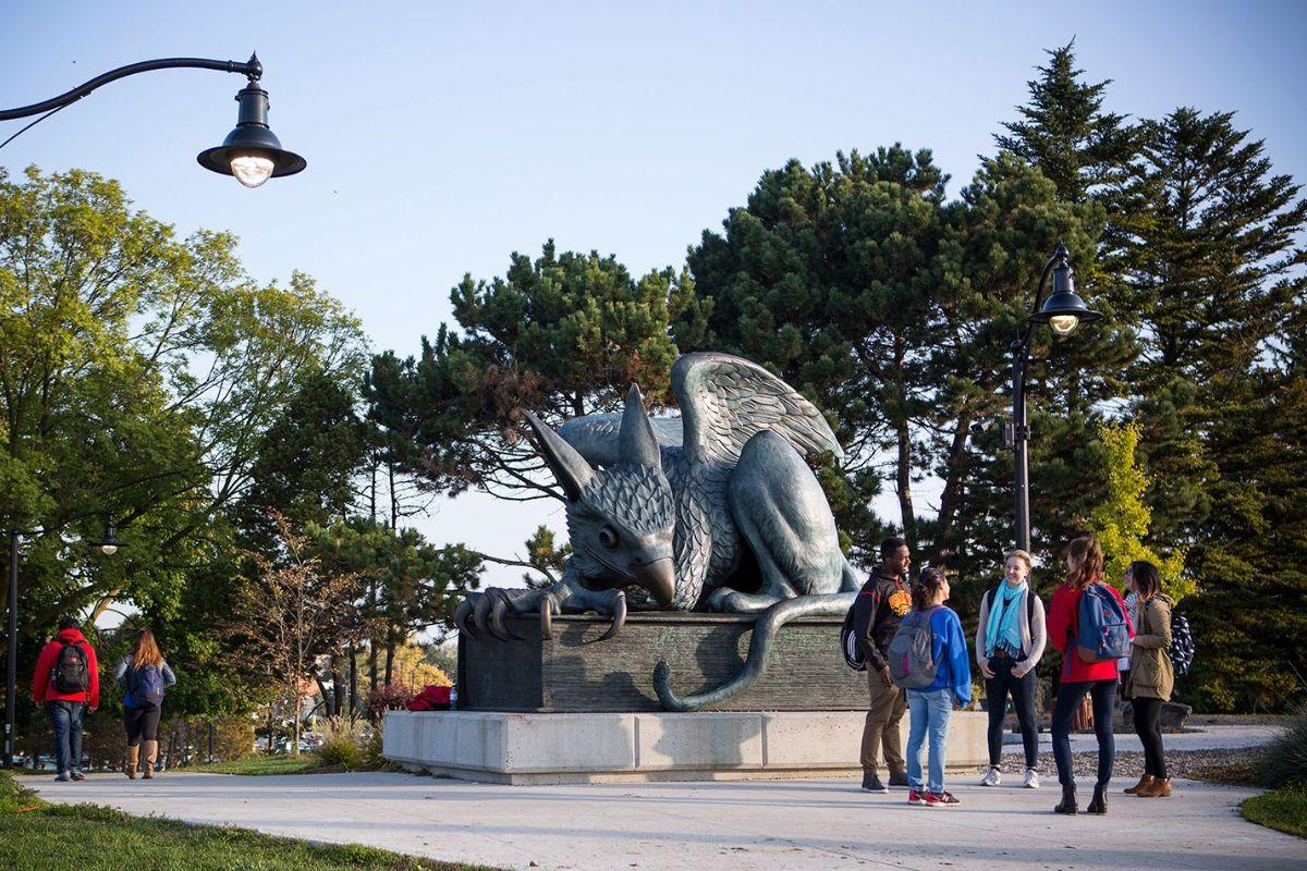 A group of grad students gathered together by the gryphon statue outside