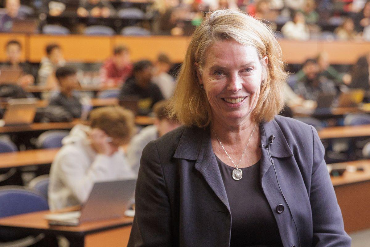 Female professor poses for a picture with a large lecture hall in the background