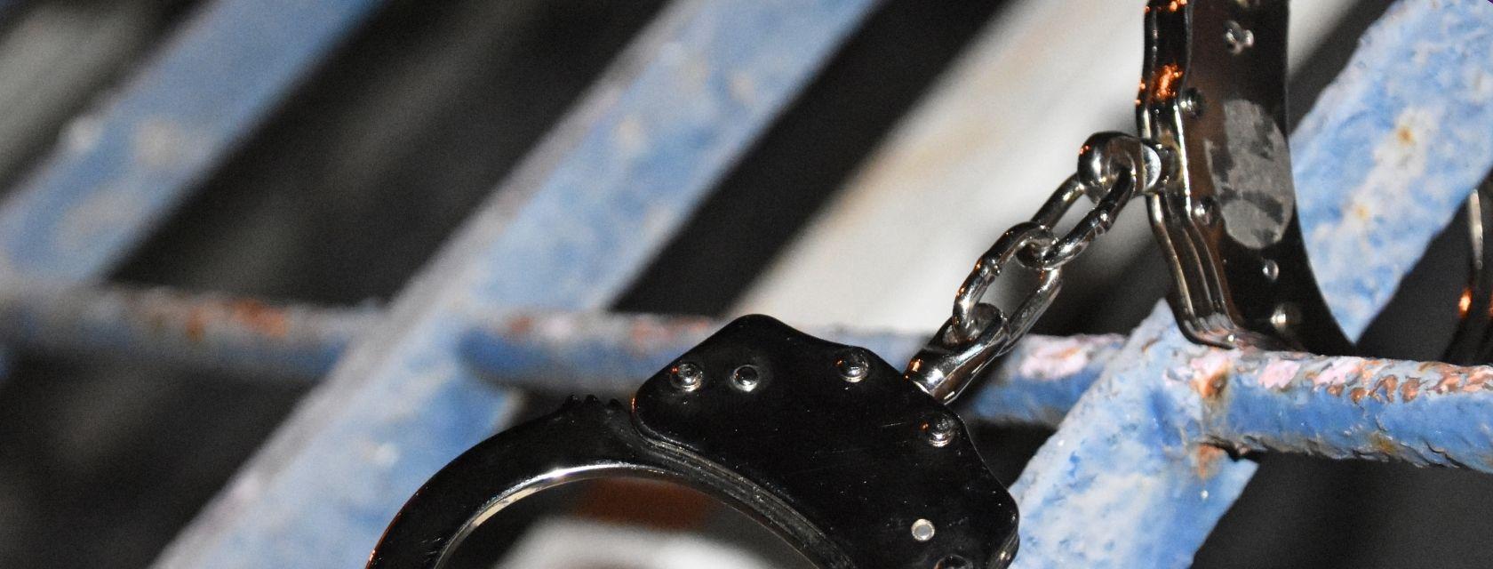 Close up shot of jail cell bars and handcuffs