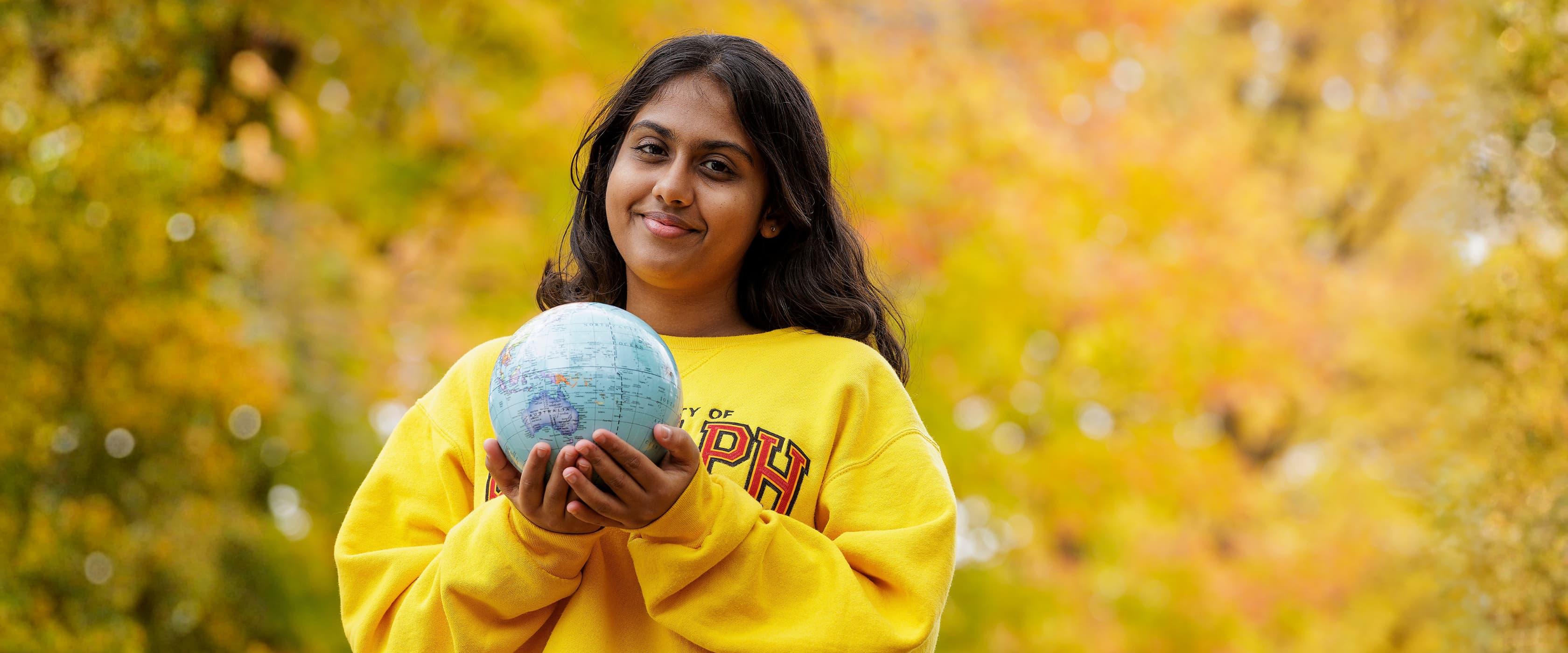 An Indian student holding a globe