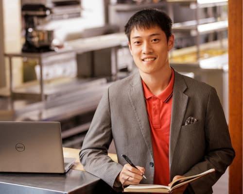 Student in suit holding notebook