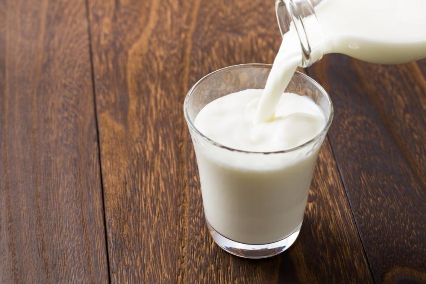 Glass bottle of milk being poured into a glass.