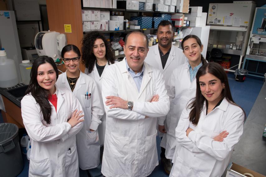 Dr. Shayan Sharif and six members of his lab pose in lab coats