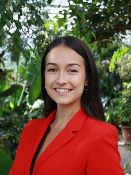 Headshot of Emily Sousa standing in front of a forested background.