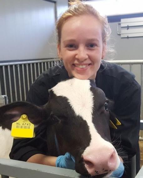 Photo of Anna Welboren resting her head on a dairy calf