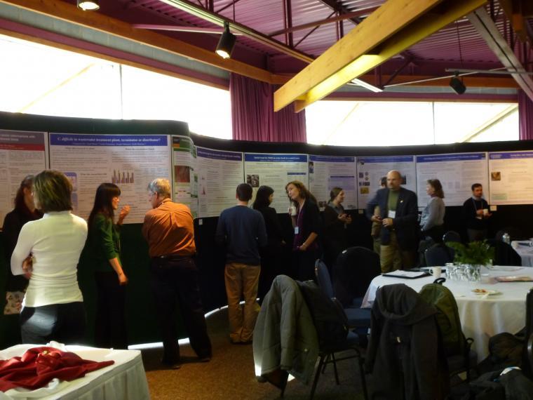 Researchers talking to students in front of a series of scientific posters