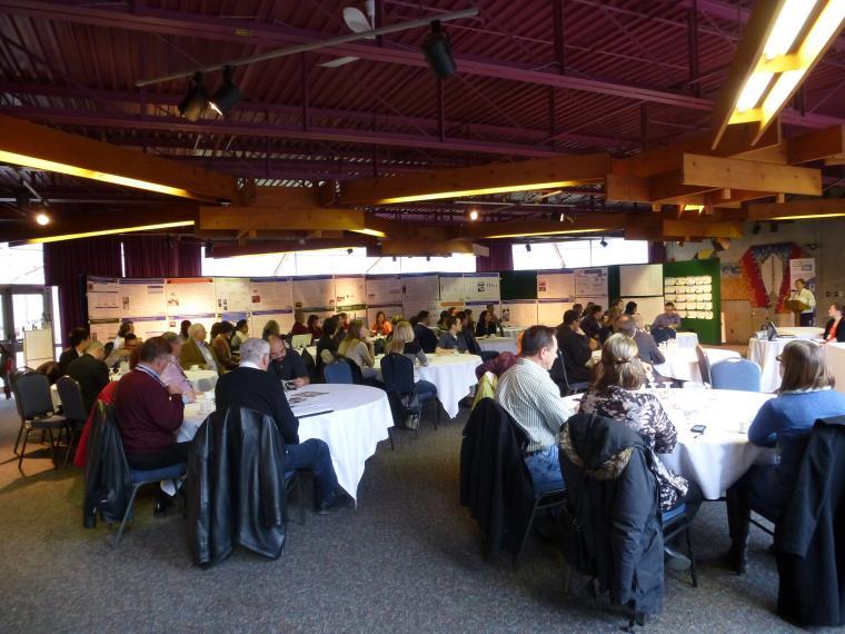 People sitting around round tables listening to a presentation