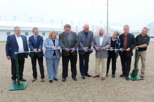 Photo of government, industry and U of G officials cutting a ribbon in front of the Ontario Swine Research Centre