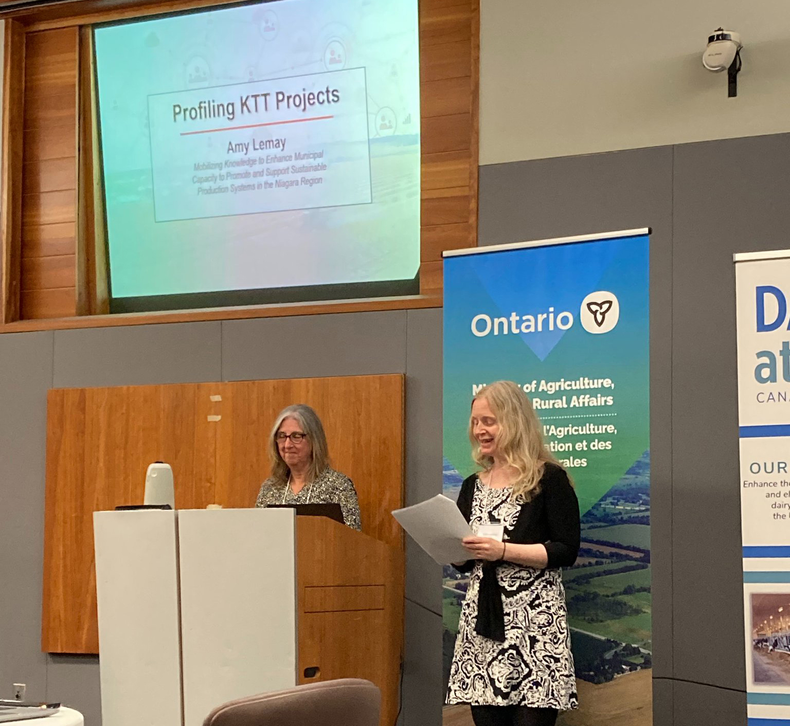 Dr. Alison Duncan standing beside Dr. Amy Lemay at the podium with Ontario banner behind them.