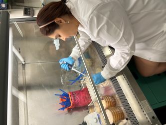 Parnia Farsingejad, wearing a lab coat, pipettes under a fume hood