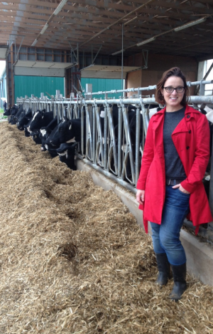 Dr. Christine Baes stands in hay at the dairy barn