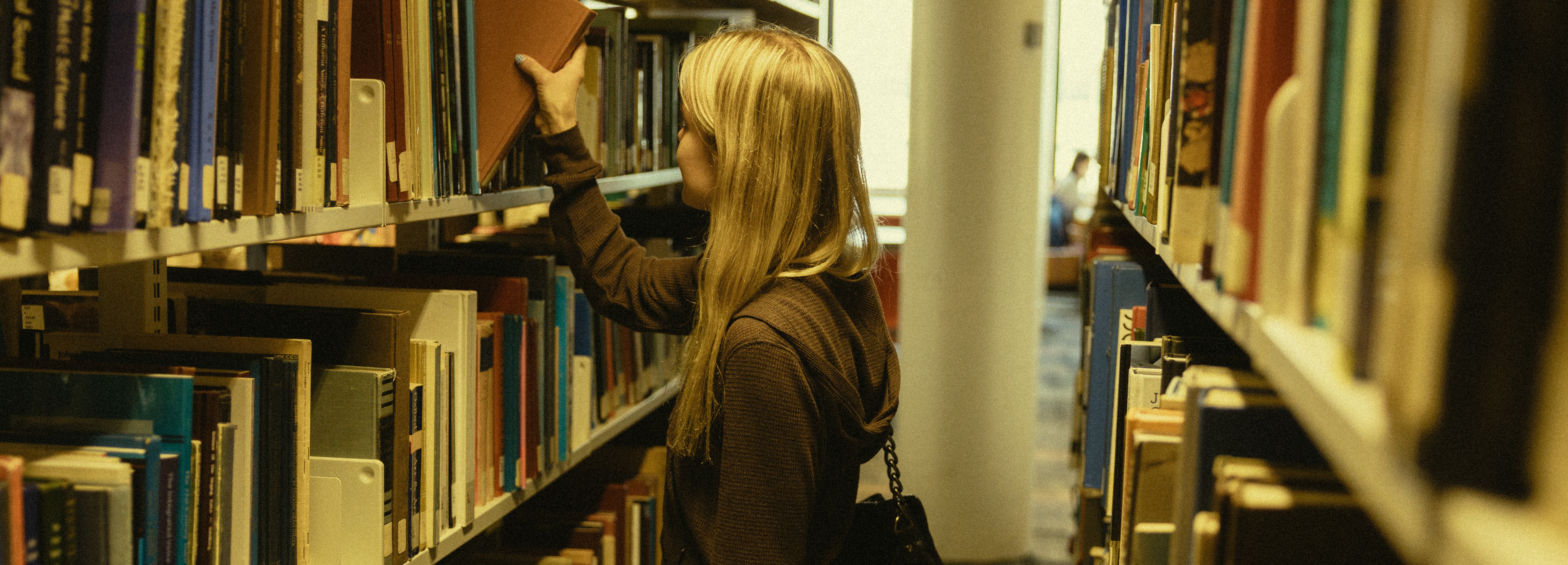 Student reaching for a book in the library
