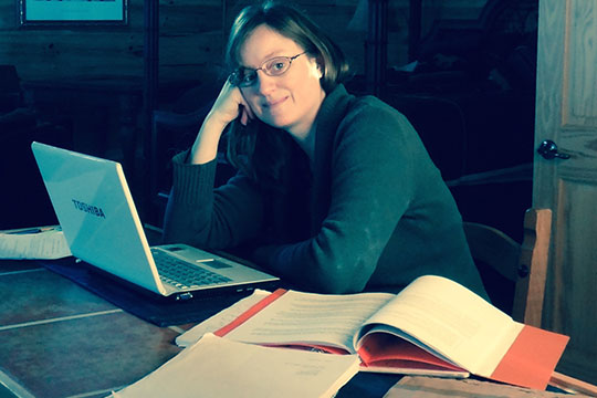 Lauren Carter seated at her desk with her laptop.