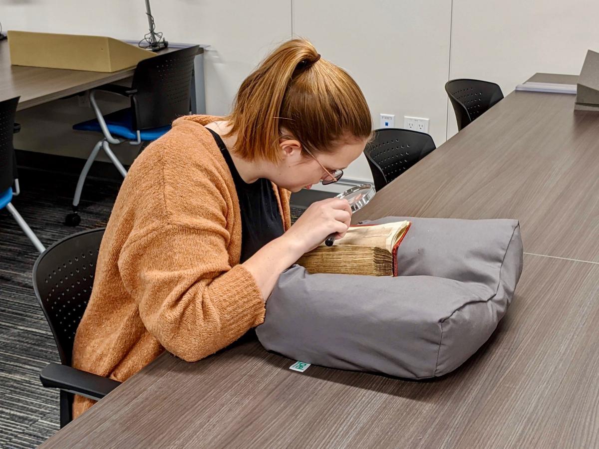 Student viewing history book with magnifying glass