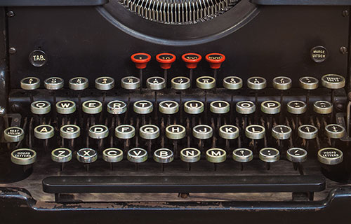 typewriter keyboard with silver round keys and four other red keys