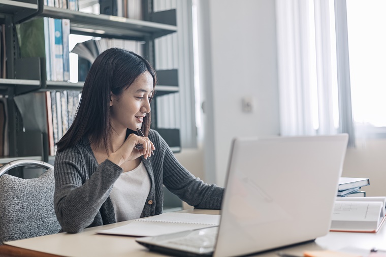 A person sitting at a desk with a computer and books