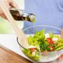 Person pouring a dressing onto a salad