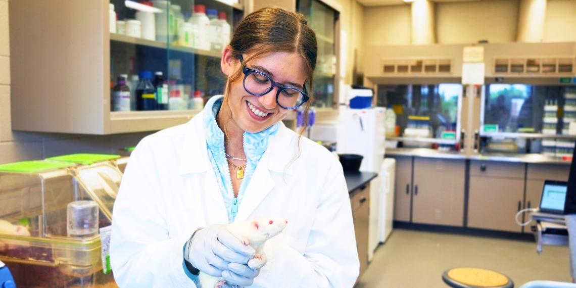 Alex Kirkup holds a rat in the lab