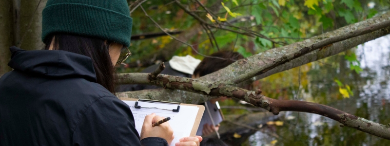 Student working on assignment near pond
