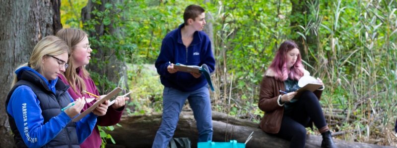 Students look at pond and take notes on clipboards