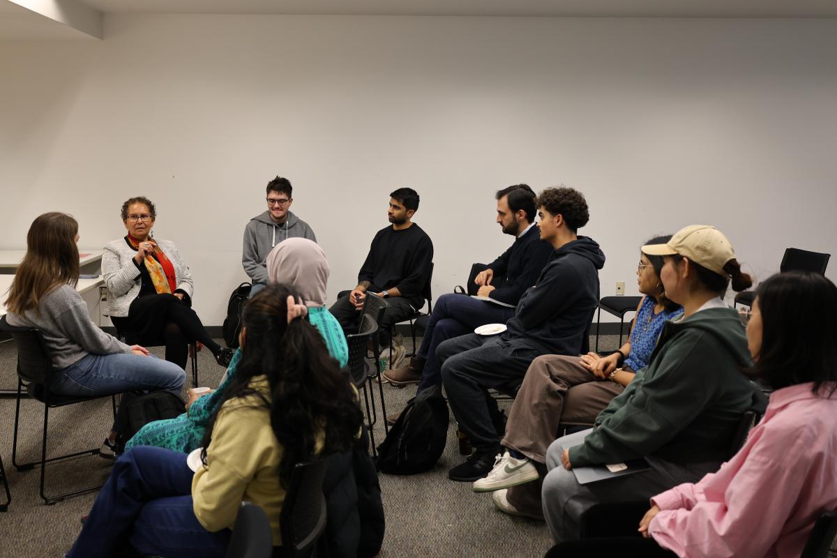 Dr. Dean sitting with a group of graduate students talking.
