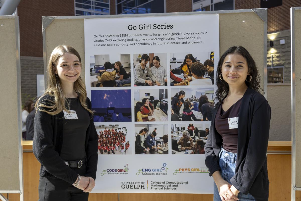 Two students, Grace and Sofia, stand with a Go Girl Series poster.