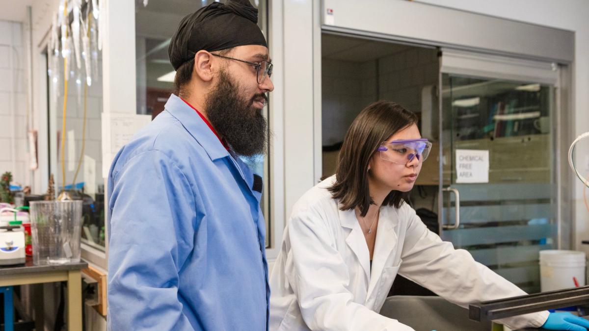 Jagandeep Saraya, PhD Candidate and Abby Sham, MSc Candidate looking at a computer screen in the chemistry lab.