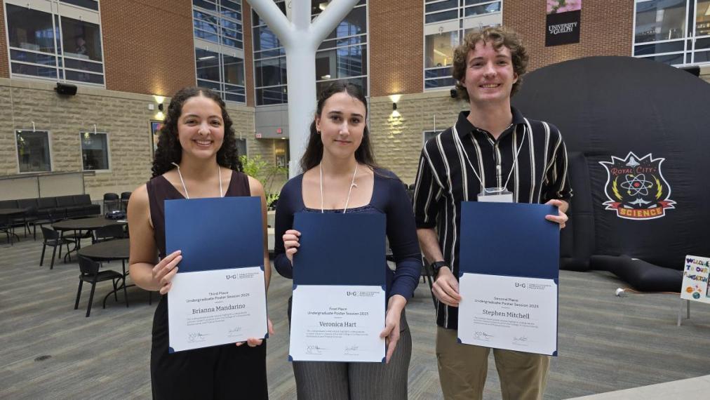 Three students standing together with certificates.