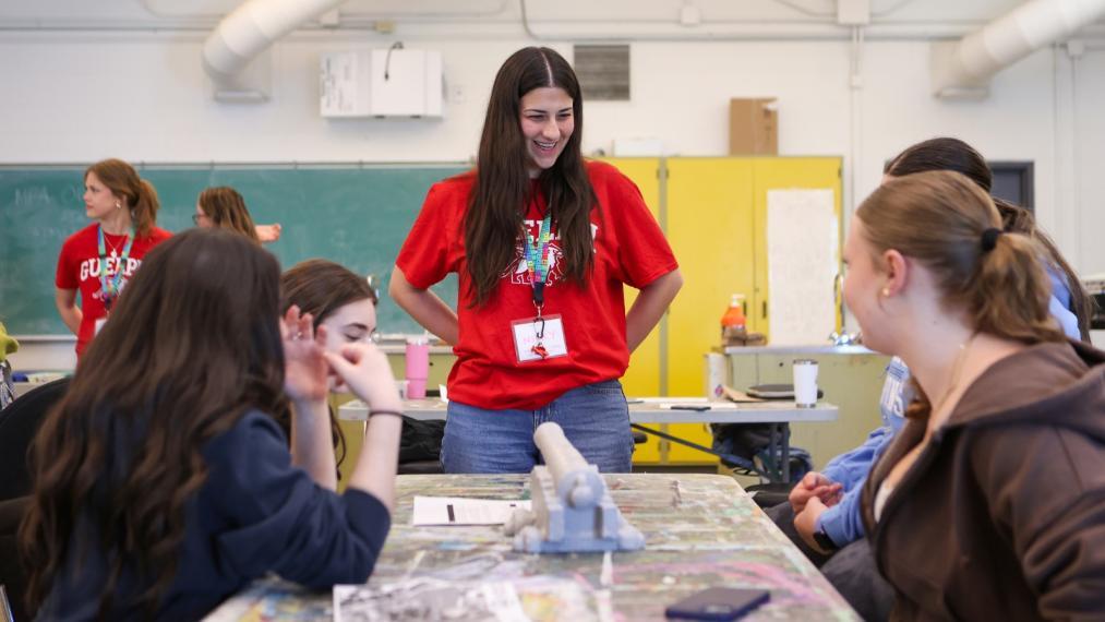 A U of G volunteer smiling while chatting with BattleSTEM participants.