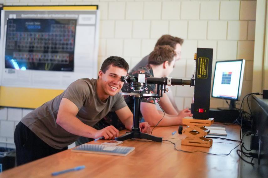 A student bending down to look through a piece of physics technology.