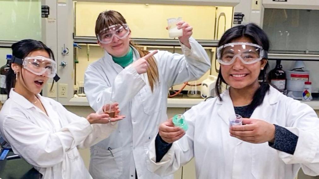 Dana Velasco (right) with her two classmates, smiling and posing for the camera in the chemistry lab.