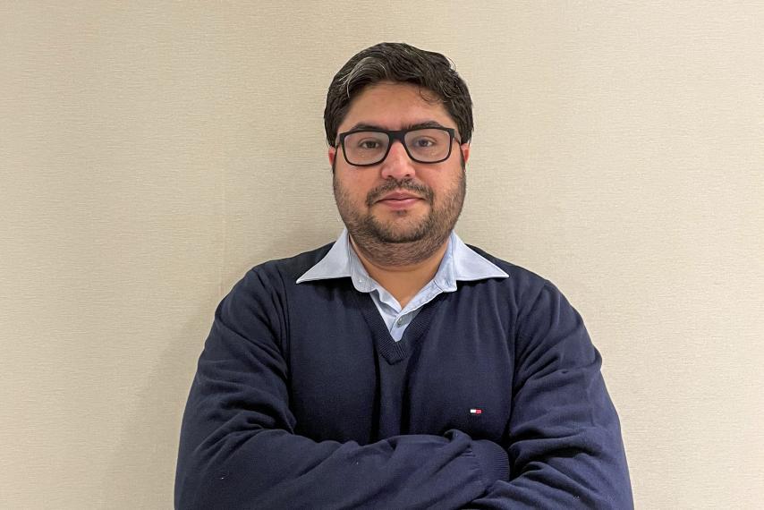 Image of man in blue long-sleeved shirt crossing his arms and looking at the camera.
