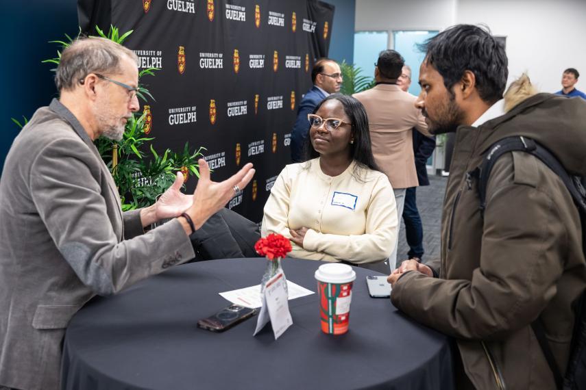 Three people standing at a table talking.